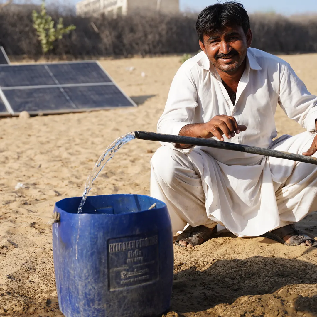 A farmer drawing water from a solar-powered pump